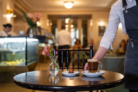 Así es el bar escondido del Teatro Colón que muy pocos conocen y el secreto foodie mejor guardado Una de las mozas sirve una mesa en la confitería Pasaje de los Carruajes en el Teatro Colón.