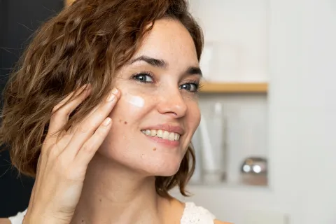 Día Mundial del Cuidado de la piel: guía para armar tu rutina de skincare según tu edad Mujer colocándose crema hidratante.