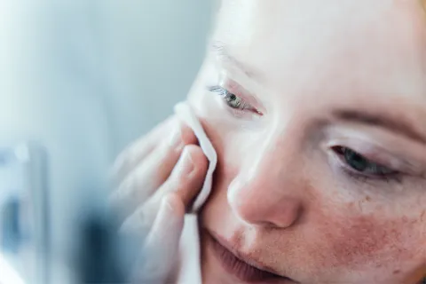 Soy dermatólogo y estas son las 10 cosas que no podés olvidar sobre la limpieza de tu piel Mujer pasándose un tónico por la cara.