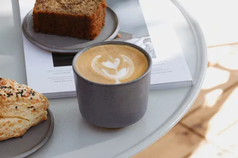 Café de especialidad: 10 cafeterías de Buenos Aires que no deberías perderte Café con leche y un pedazo de budín.