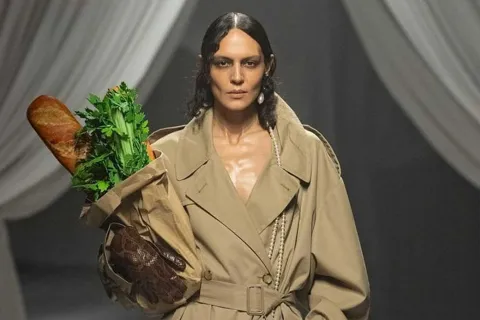 Así es el bolso con forma de pan de Moschino que cuesta 1200 euros La modelo lució sobre la pasarela un trench por debajo de la rodilla en color camel y un collar de perlas