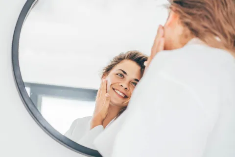Colágeno: estas son las formas de suplementarlo y los beneficios de consumirlo Mujer mirándose al espejo.