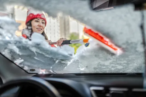 Cómo descongelar y sacar escarcha del parabrisas del auto Mujer descongelando el parabrisas.