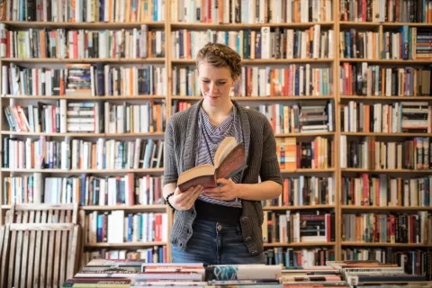 5 libros increíbles que, después de leerlos, no vas a dejar de recomendar mujer leyendo un libro en una librería.