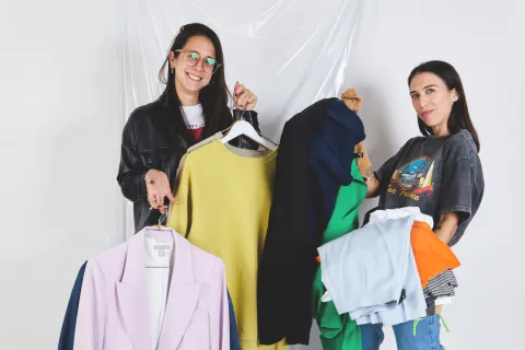 Moda circular: los mejores 10 locales para comprar ropa con onda y muy barata Dos chicas sosteniendo perchas con ropa.