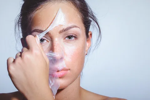 Mujer sacándose una máscara facial.