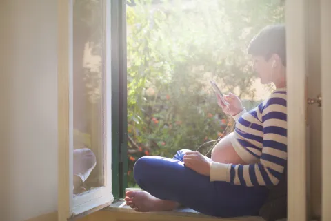 6 pódcasts de maternidad que cuentan el lado de B de ser madres (y que no deberías perderte) Mujer embarazada escuchando un pódcast.