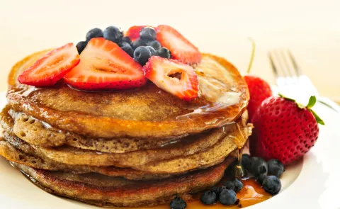 Fáciles, ricos y nutritivos: la receta de pancakes de avena y manzana de Paulina Cocina ideal para desayunar Un plato de pancakes con miel, frutillas y arándanos