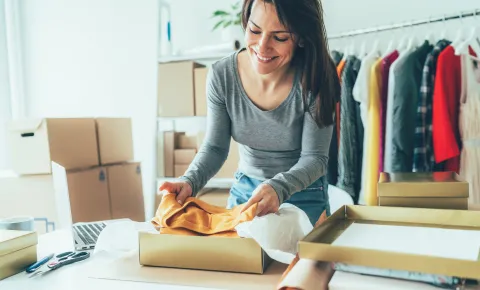 El paso a paso para comprar ropa en el exterior y que llegue a la puerta de tu casa Una mujer abriendo una caja con ropa
