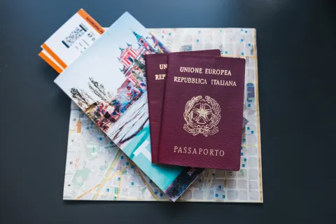 Ciudadanía italiana: cómo tramitarla por bisabuelos o matrimonio y qué beneficios tiene Dos pasaportesitalianos apoyado sobre un mapa