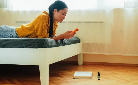 ¿Hay algo más cruel que el ghosting?: qué es el cloaking y en qué consiste Mujer tirada en la cama mirando el teléfono celular
