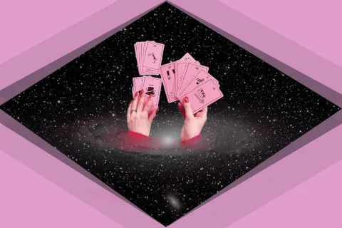 Conocé el consejo energético del tarot para la semana del 30 de septiembre: elegí una carta y descubrilo Unas manos sosteniendo unas cartas de tarot en un fondo de galaxia.