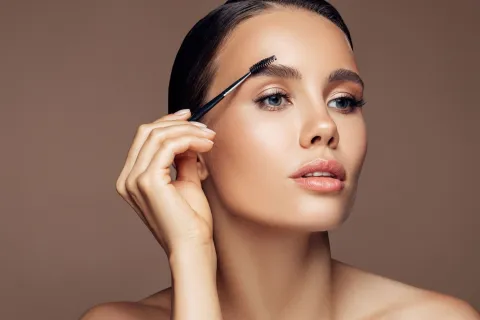 Cuánto cuesta hacerse nanoblading, la nueva técnica para las cejas Una mujer peinándose las cejas con un cepillo