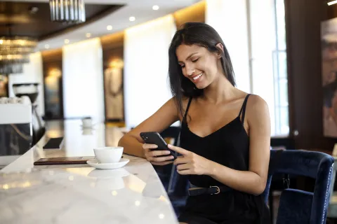 ¿Qué significa que una persona llegue temprano a todos lados, según la psicología? Mujer con celular en un bar