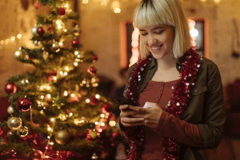 ¿Cómo desconectarte de las redes sociales durante las fiestas? Claves para un “detox digital” mujer con celular en Navidad
