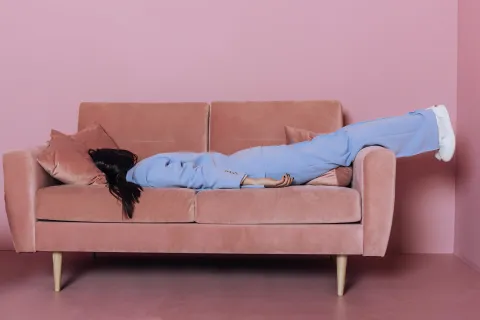 El "gran cansancio": ¿de qué se trata esta tendencia y cómo cambiarán nuestros consumos? Una mujer cansada tirada acostada en un sillón.