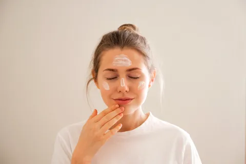 Por qué se debe usar protector solar facial todos los días y cada cuánto reaplicarlo Una mujer aplicandose crema en la cara
