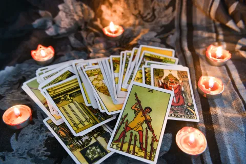 Predicciones 2025: elegí una carta del tarot y descubrí cuál será tu mayor desafío el próximo año Un mazo de tarot sobre una tela y unas velas encendidas.