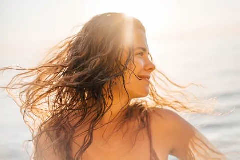 Pileta, sol y mar: los trucos para cuidar el pelo durante el verano y que crezca sano y fuerte Una mujer con el pelo mojado disfrutando de un día de playa