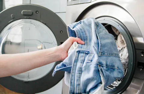 una mujer sacando jeans del lavarropas