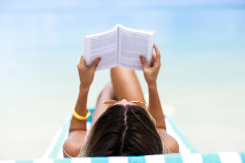 Novelas, cuentos y no-ficción: los 8 libros que no pueden faltar en tu verano Una mujer leyendo en la playa