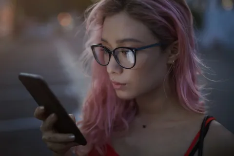 ¿Necesito anteojos? Conocé cuáles son las señales que indican que necesitás lentes mujer joven con anteojos mira el celular