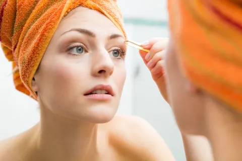 'Lion Mane': cómo lograr la tendencia en maxi cejas que es súper natural y fácil de mantener Una mujer depilándose las cejas