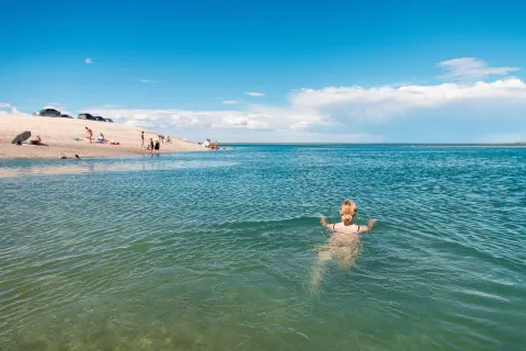 El Caribe argentino: las 3 playas con agua cristalina ideales para vacacionar Fotografía de una chica nadando en un mar cristalino y de lejos se ve la arena blanca con un par de personas