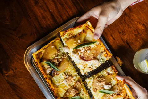 Día de la Pizza: estas son las mejores versiones para disfrutar de este clásico en Buenos Aires Una mano tomando porciones de pizza.