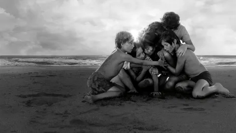 Una mujer abrazada por un grupo de niños en la playa.