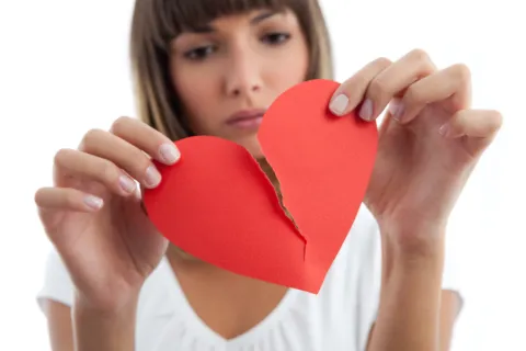 Señales de que una relación ya no te hace bien: qué mirar más allá de la pasión Foto de mujer rompiendo corazón de papel.