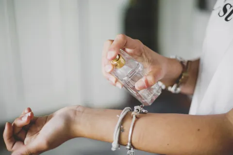 Una mujer poniendose perfume en la muñeca