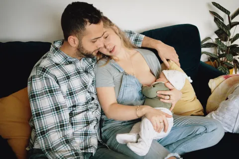 una mujer le da el pecho a su bebés y el marido acompaña