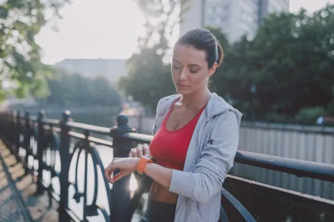 mujer mira el reloj para controlar el tiempo de entrenamiento