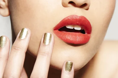 Tendencias 2026: los labios full color se convierten en los grandes protagonistas del maquillaje Una mujer con los labios en color rojo y las uñas doradas