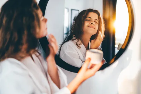 una mujer poniendose crema en la cara 