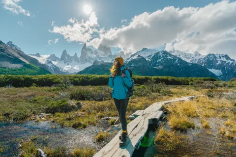 No vayas donde va todo el mundo en vacaciones de invierno: 5 destinos en Argentina que te van a sorprender Una mujer vestida con ropa de trekking en un sendero cercano a las montañas.