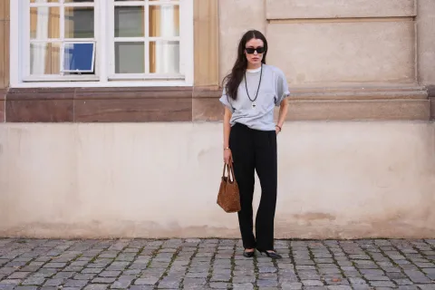 Los pantalones negros de los años 90 volverán a estar de moda: ¿cómo vamos a usarlos? Una mujer parada en la calle con remera corta y pantalones negros
