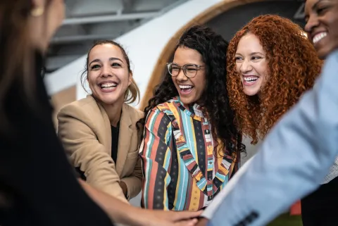 mujeres juntan manos en el trabajo