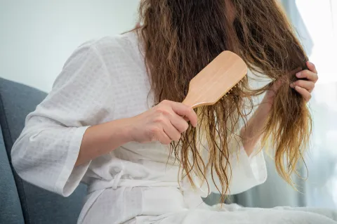 ¿Pelo fino y dañado? Los hábitos que ayudan a recuperar el volumen y la densidad, según un experto Una mujer peinándose en bata