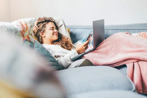 mujer joven en casa con tecnología tapada por el frio