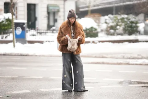 Una mujer con un jean gris y un saco de pelo en color marrón