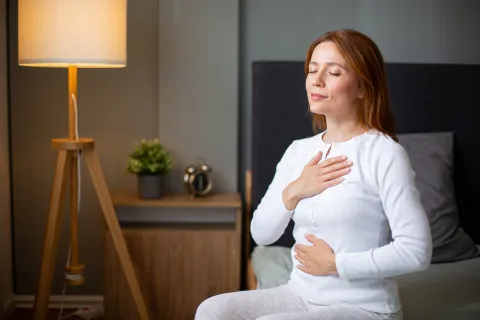 Fertilidad y salud: por qué cuidar tu fertilidad aunque no quieras ser mamá mujer tranquila medita y respira en su cama