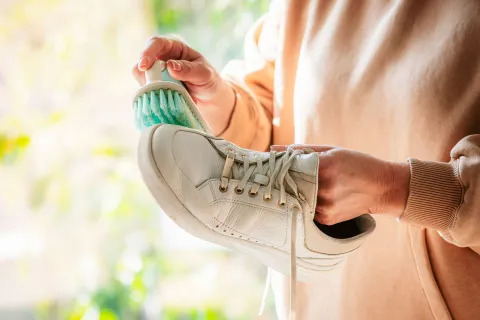 Cómo eliminar el mal olor de calzados y zapatillas Mano lavando zapatilla de cuero blanca