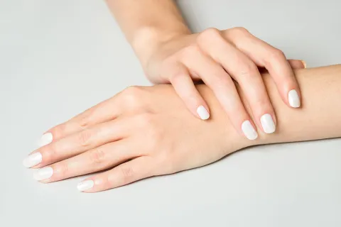 Manicura “manos caras”: 5 colores de esmalte elegantes que estilizan las manos Manos pintadas con esmalte color crudo sobre fondo blanco