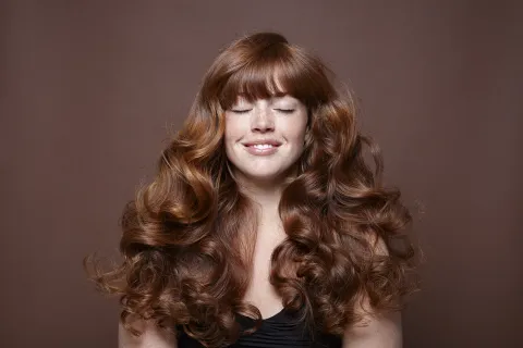 Pelo con rulos: los consejos de un estilista para hidratar, definir y controlar el frizz Una mujer con rulos con los ojos cerrados