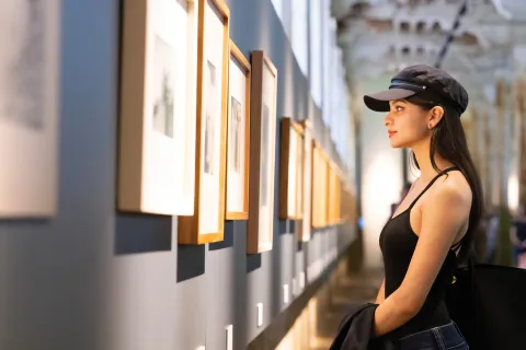 De Palermo a La Boca: 5 museos que merecen un lugar en tu agenda Mujer observando cuadros en una muestra de arte.