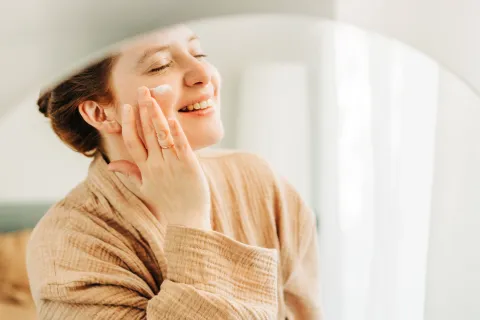 Una mujer poniéndose crema en la cara