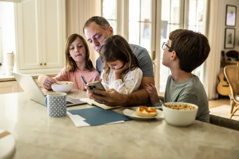 padres con chicos en la mesa con computadora y teléfono