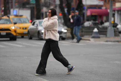 Una mujer cruzando la calle en nueva york con ropa bien abrigada
